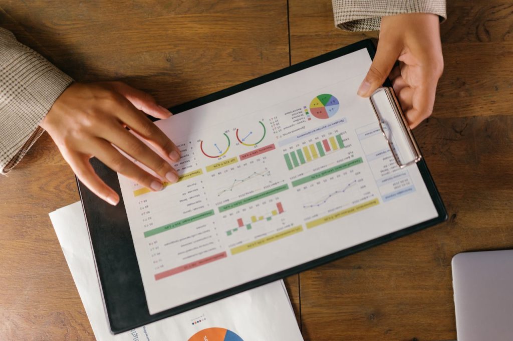 charts-and-graphs-on-paper-on-a-clipboard-9304917 Top view of hands holding a financial report with colorful graphs and charts, ideal for business presentations.